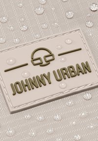 Fehér szövet, textúrált mintával, tiszta vízcseppek találhatók rajta. Egy emelt, olajzöld logóval, amelyen az áll, hogy "JOHNNY URBAN", grafikai elemmel.