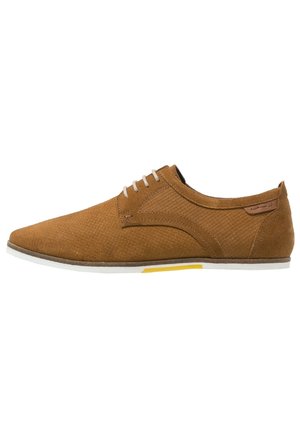 Brown suede shoe with a textured upper, slim silhouette, light grey laces, and a white sole featuring a yellow accent.