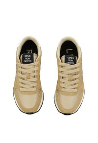 Beige Sport Schuhe mit einem glatten Textil-Obermaterial, Wildleder-Elementen, runden Schnürsenkeln und einer bedruckten Innensohle, auf der "MÄDCHEN LAUFEN SCHNELLER" steht.