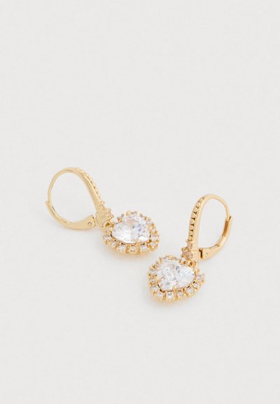 Cercei cu lăbuță aurie, având un centru mare din cristal transparent, înconjurat de cristale mai mici transparente într-un design floral.