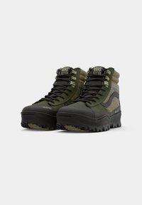 Green and black high-top Vans MTE hiking boots with Gore-Tex fabric and thick Vibram soles, angled front view on white background.