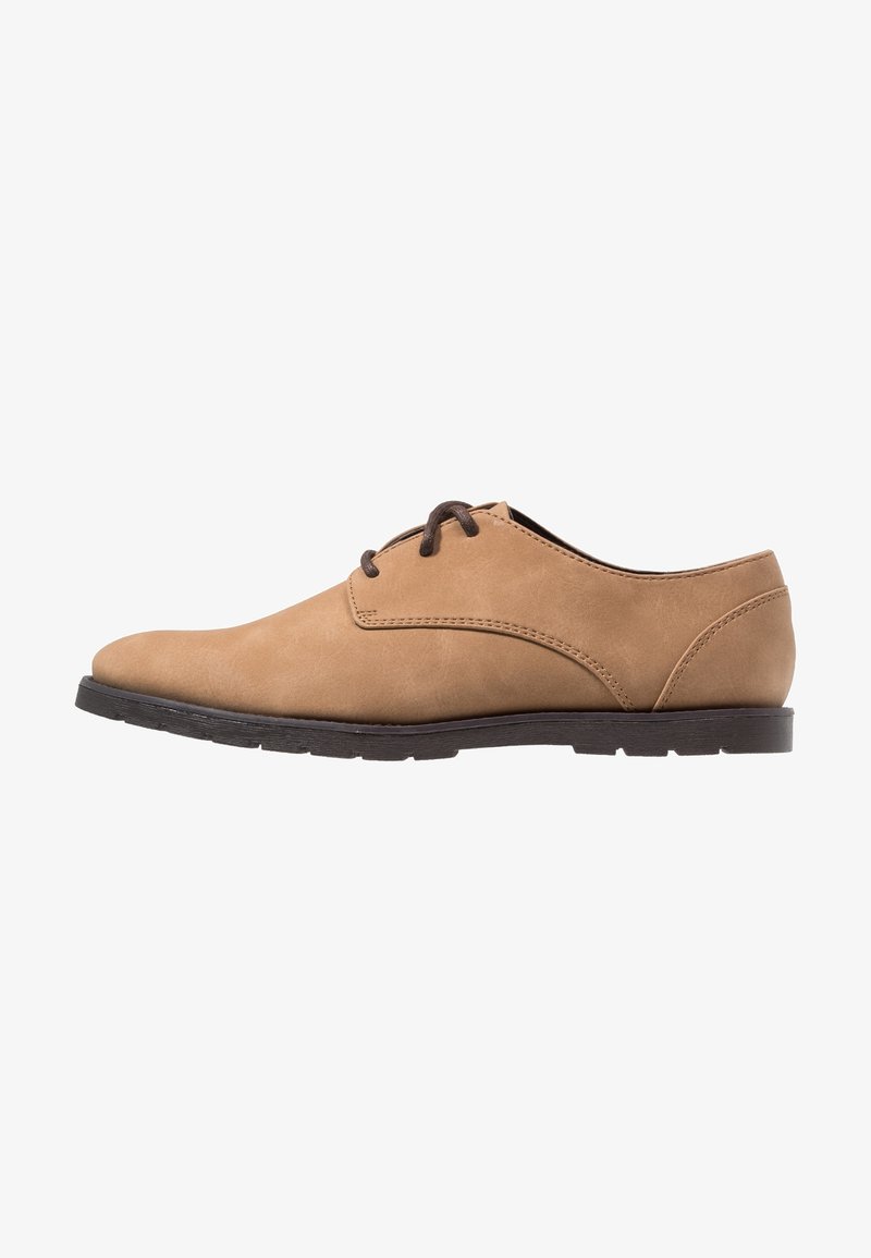 Chaussure habillée pour homme en cuir marron clair, à lacets, avec semelle noire, vue de profil sur fond blanc.