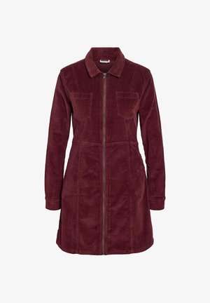 Vínová manšestrová košilová šaty s dlouhými rukávy, předním zipem, dvěma kapsami na prsou a špičatým límcem. Texturovaná tkanina se jemným povrchem.