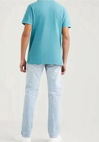 Ljusblå kortärmad t-shirt i bomull, tillsammans med ljus tvättade jeans. Enkel design, avslappnad passform, bärs med vita sneakers.