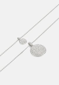 Colier din metal argintiu, având un pandantiv circular mai mare și un pandantiv rotund mai mic, ambele împodobite cu pietre prețioase clare, intricate.