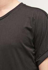 Camiseta negra de manga corta con cuello redondo, confeccionada en suave algodón con una textura lisa y un corte relajado.