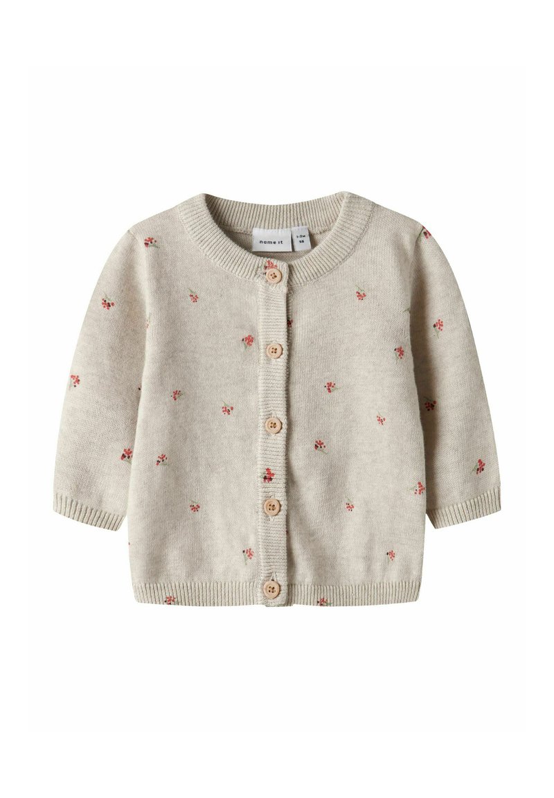 Bež otroški kardigan z dolgimi rokavi, lesenimi gumbi spredaj in majhnimi rdečimi cvetličnimi vzorci, raztresenimi po tkanini.