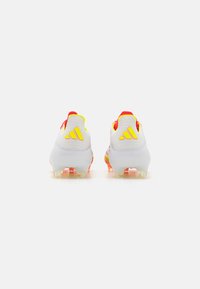 Ghetele de fotbal Adidas prezintă o scheme de culori alb și galben strălucitor, cu un superior texturat și un accent vibrant pe călcâi. Puncte transparente.