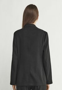 Svart skräddarsydd blazer med en lång, rak silhuett, skarpa slag och långa ärmar. Slät tyger med en finish utan synliga detaljer.