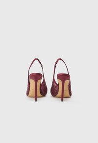 Burgundske visokotlačne čevlje z satenskim zgornjim delom in okrasnimi žebljički. Odprti hrbet in vitka gležnjačka priponka. Stiletto peto z teksturiranimi podrobnostmi.