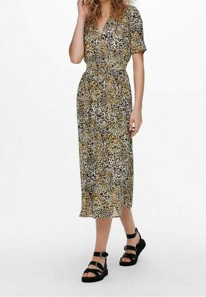Leopardenmuster Kleid mit Wickeldesign, kurzen Ärmeln und tailliertem Bund. Midi-Länge, leichtes Material, kombiniert mit schwarzen Riemchensandalen.
