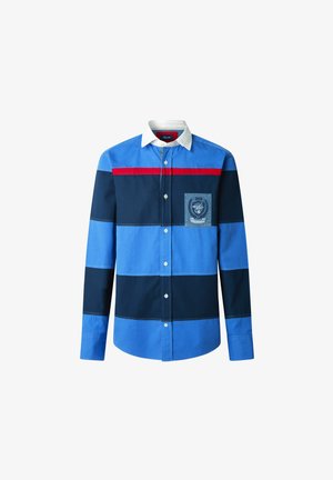 Chemise rayée bleue et marine avec accent rouge, devant boutonné et col blanc. Comprend une poche poitrine avec un emblème bleu et des détails de couture.