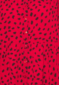 Red dress featuring a textured fabric with black brushstroke patterns, button front, and gathered skirt detail.