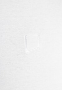 Biała bawełniana tkanina o subtelnej fakturze; posiada małą, kwadratową łatę przyszytą do materiału. Prosty i minimalistyczny wzór.