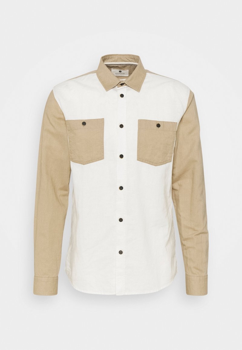 Camicia con bottoni caratterizzata da un corpo bianco e maniche beige, con due tasche frontali, bottoni scuri e un design con colletto classico.