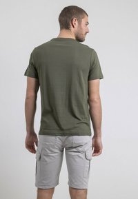 T-shirt en coton vert olive à manches courtes, col ras du cou et ourlet droit, associé à un short cargo gris clair avec poches latérales.