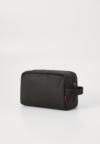 Trousse de toilette en tissu noir de forme rectangulaire, surface texturée, fermeture éclair et poignée latérale pour un transport facile.