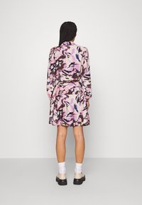 Blumenkleid mit langen Ärmeln, das eine Mischung aus rosa, lila und braunen abstrakten Mustern zeigt. Weicher Stoff mit tailliertem Schnitt und ausgestellt Rock.