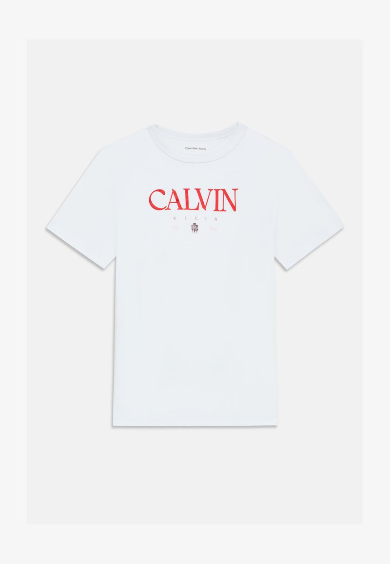 Balta kokvilnas T-kreklu ar īsām piedurknēm, ar sarkanu "CALVIN KLEIN" logotipu priekšpusē. Klasiska apaļa apkakle, bez papildu rakstiem vai akcentiem.
