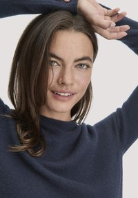 Marineblauer Rundhalsausschnitt-Pullover aus weichem, strukturiertem Stoff, mit langen Ärmeln und lockerer Passform, sowie dezentem Nähedetail am Halsausschnitt.