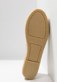 Podeszwa buta z gumowego kauczuku, żebrowana faktura i oznaczenie rozmiaru 37. Beżowe wykończenie z zaokrąglonymi krawędziami, zaprojektowana dla trwałości i przyczepności.