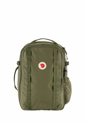 Sac à dos rectangulaire vert avec poignée supérieure, deux sangles verticales, plusieurs compartiments zippés et un patch rond rouge et blanc avec logo.