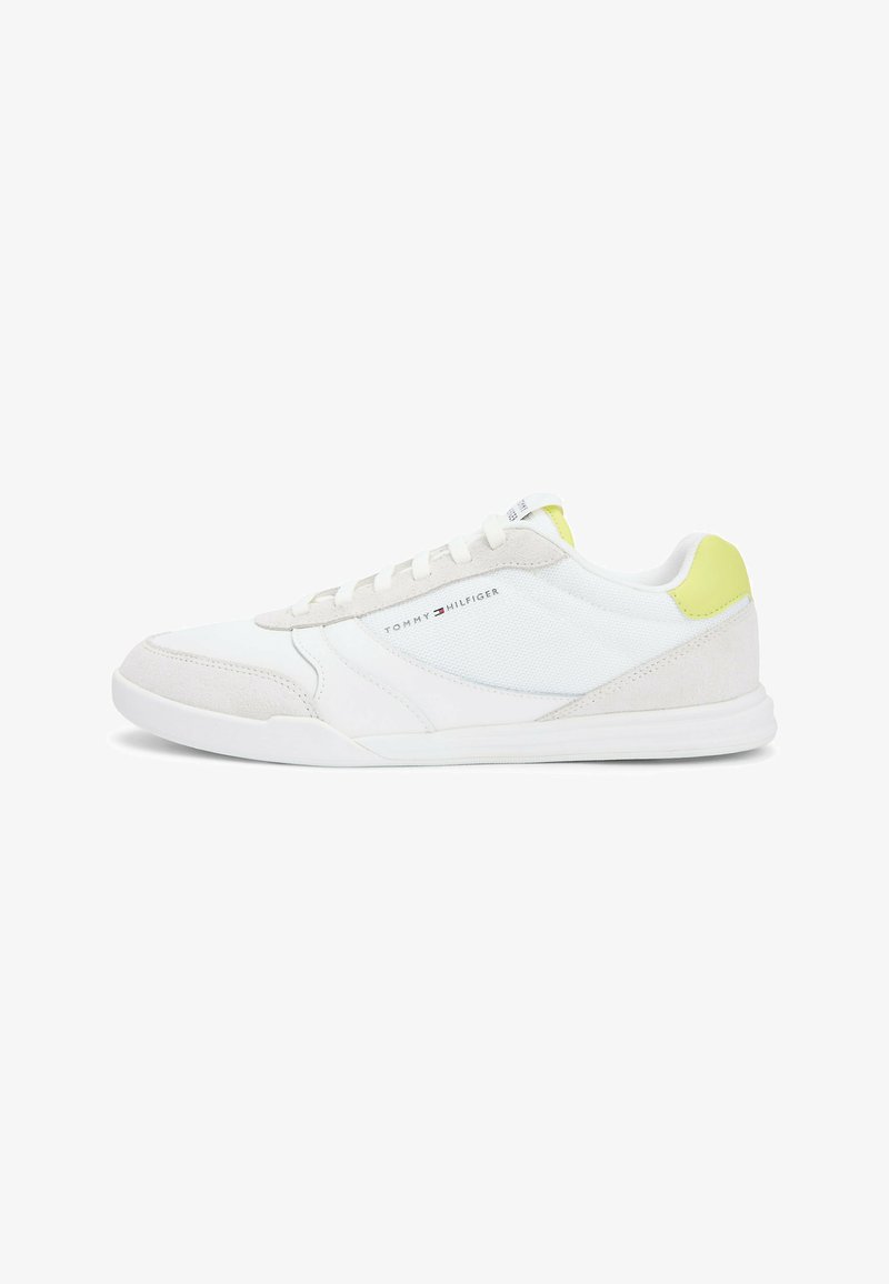 Baskets basses blanches avec détails en daim et mesh, design à lacets, accent jaune au talon, et logo Tommy Hilfiger sur le côté.