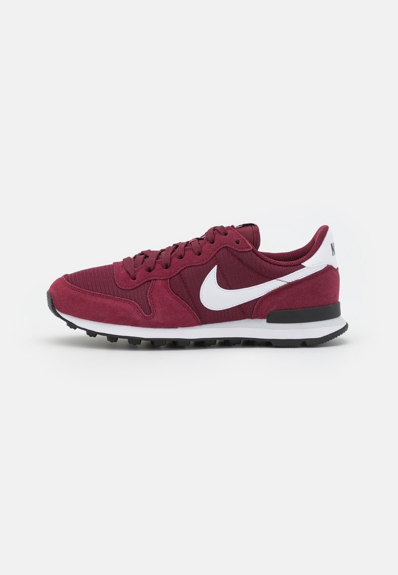 Bordowe sneakersy z teksturowaną górną częścią z materiału, białym logo Nike i czarną gumową podeszwą. Wyposażone w sznurowadła i wyściełany kołnierz dla wygody.