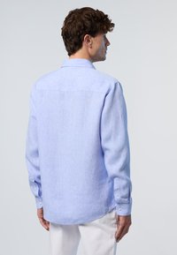 Camicia azzurro chiaro a maniche lunghe realizzata in tessuto a trama, con colletto classico e due bottoni su ciascun polsino.