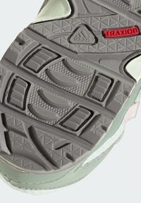 Adidase Traxion kinga tallaga omadused hõlmavad tekstureeritud halli kummi pinda, millel on kolmnurksed ja ovaalsed mustrid, piparmündiroheline ülemine äär ning punane logo detail.