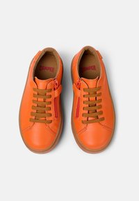 Zapatillas de piel naranja con cordones marrones, cremallera lateral y suelas de goma. Presentan una textura suave y un interior con marca.