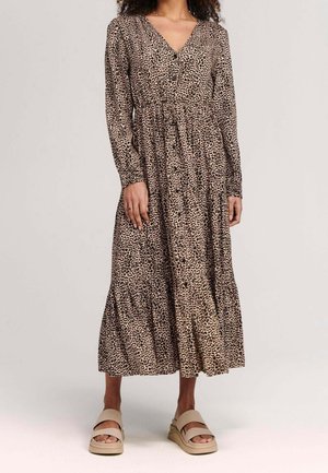 Šaty s leopardím vzorem z lehké látky, mají výstřih do V, dlouhé rukávy, stažený pas a sukni s volány. Kombinovány s béžovými sandály.