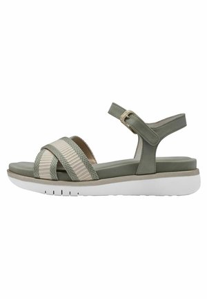 Green sandal featuring woven straps in light beige. Smooth footbed, adjustable ankle strap with gold buckle, and white rubber sole.