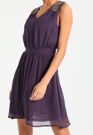 Fioletowa sukienka bez rękawów z dekoltem w serek, marszczonym pasem, spódnicą do kolan oraz zdobieniami z koralików na panelach na ramionach.