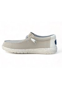 Zapato slip-on de lona beige con un acabado texturizado, acentos grises, suela blanca moteada y un sistema de cordones para un ajuste seguro.