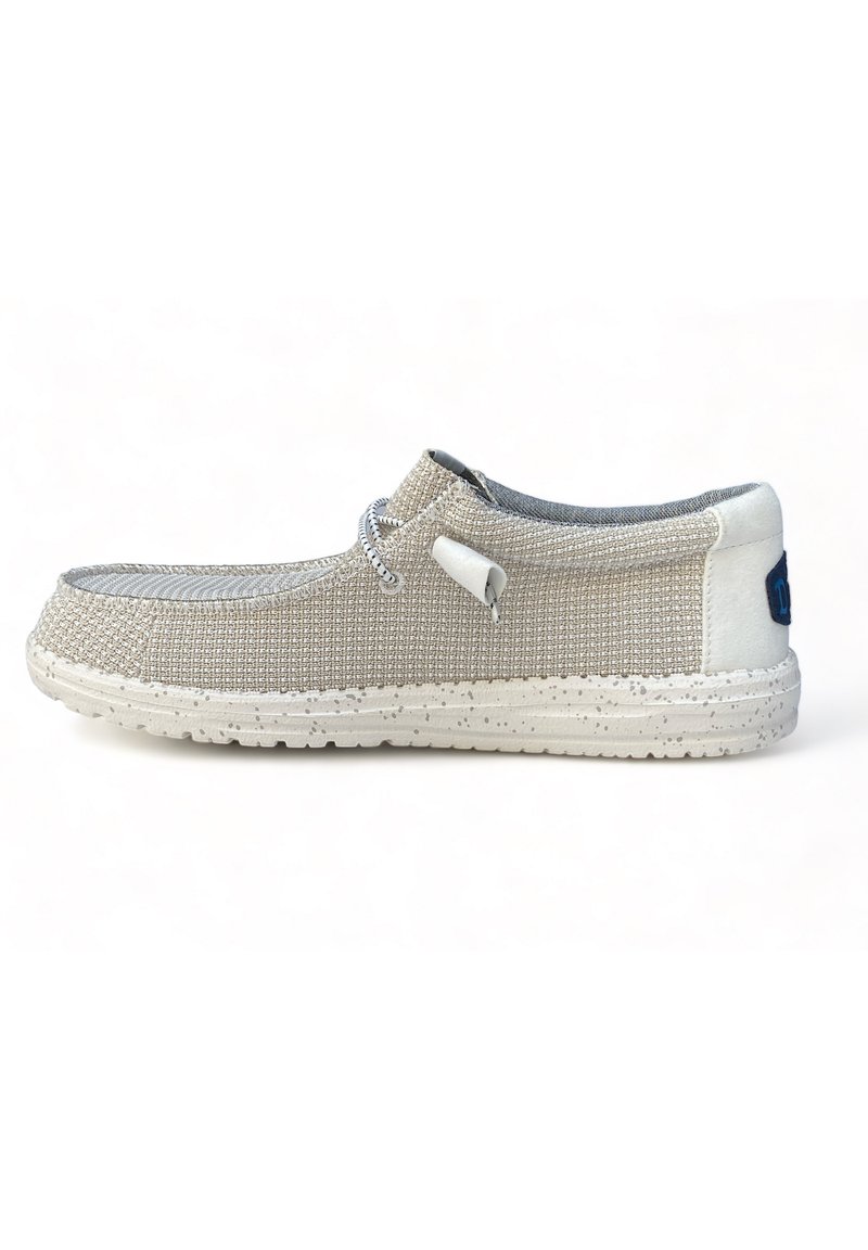 Zapato slip-on de lona beige con un acabado texturizado, acentos grises, suela blanca moteada y un sistema de cordones para un ajuste seguro.