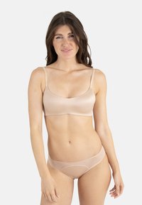 Bralette sans fil couleur nude et culottes assorties. Matériau lisse et extensible avec des bretelles fines et un design sans couture.