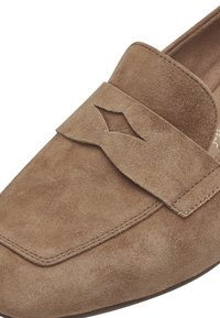 Bruine suède instappers hebben een gestructureerd oppervlak, een gevouwen accent met een uitsnijding en gestikte randen voor extra duurzaamheid.