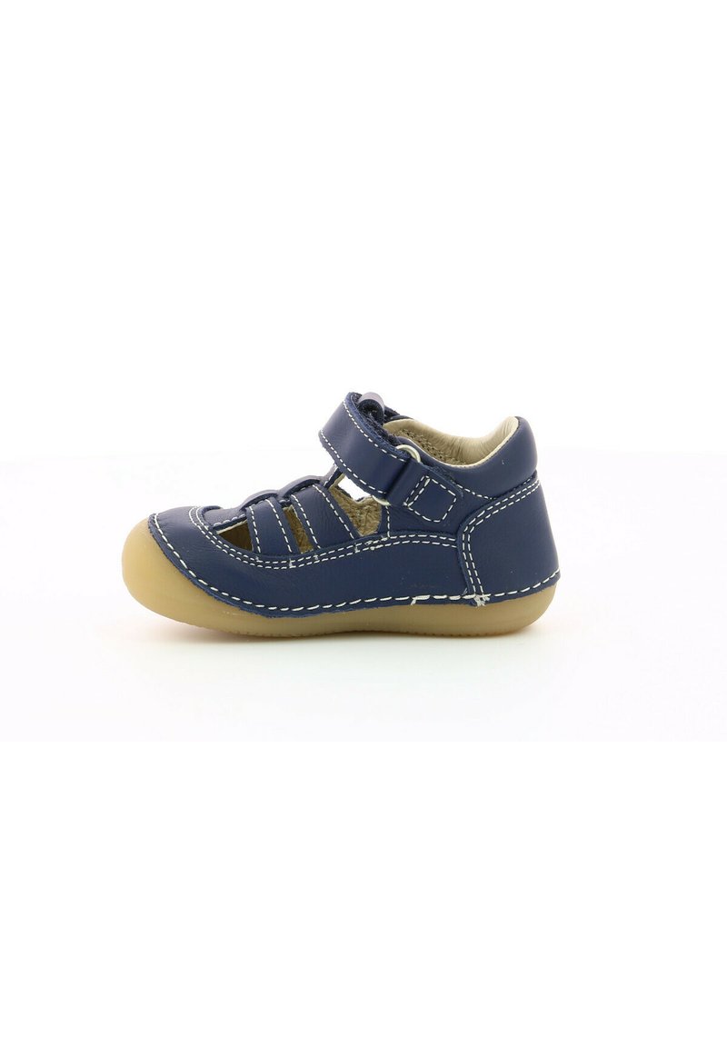 Zapato de piel azul marino con punta abierta, tira de Velcro y suela de goma beige. Incluye costuras blancas y un diseño recortado para transpirabilidad.