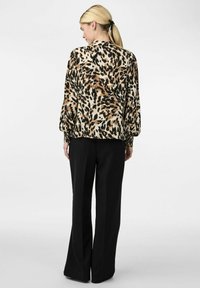 Blouse met luipaardprint, voorzien van ballonsleeves, elastische manchetten en een relaxte pasvorm, gecombineerd met wijde zwarte broek. Zachte stoftextuur.