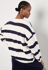 Strickpullover mit abwechselnden navyblauen und weißen Streifen, strukturiertem Muster, Rundhalsausschnitt und lockerer Passform mit überschnittenen Schultern.