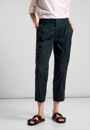Dark green cropped pants with an elastic waistband, featuring visible side pockets and a smooth texture. Paired with black leopard print sandals.
