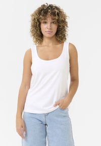 Weißes Baumwoll-Top mit Rundhalsausschnitt und breiten Trägern, kombiniert mit hellblauen Jeans aus Denim mit Seitentaschen.