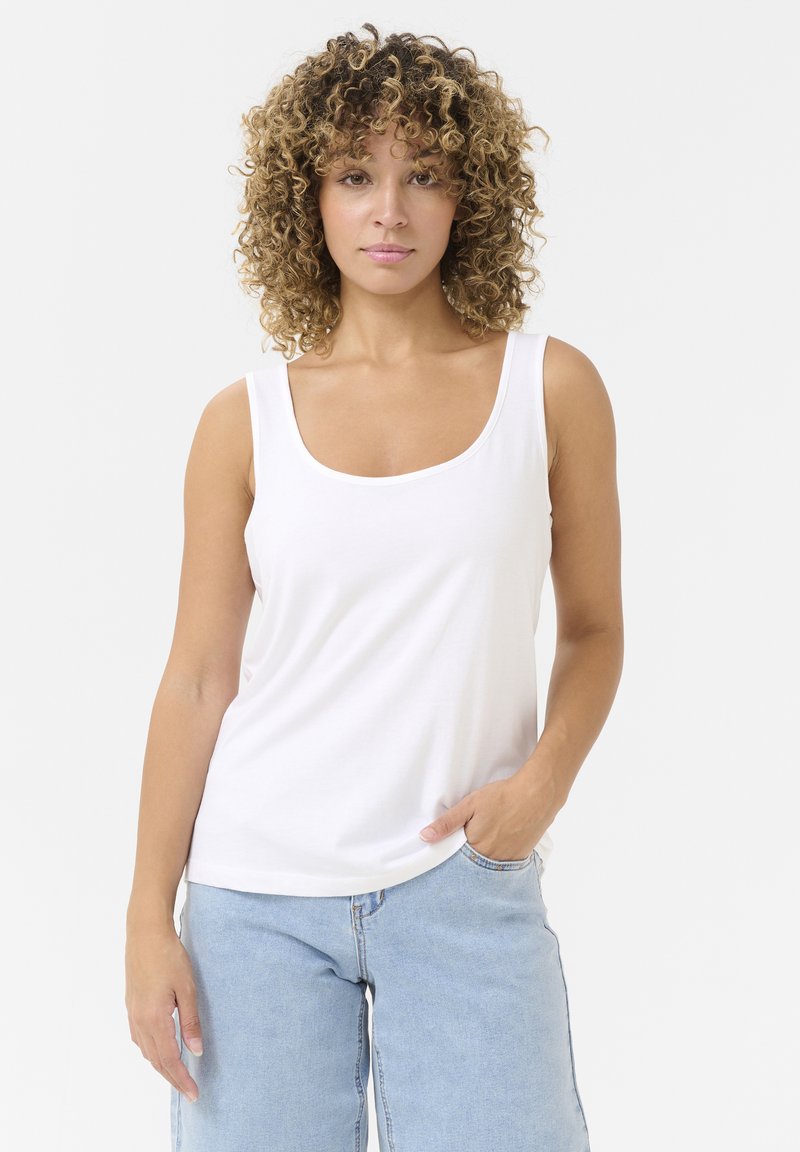 Weißes Baumwoll-Top mit Rundhalsausschnitt und breiten Trägern, kombiniert mit hellblauen Jeans aus Denim mit Seitentaschen.