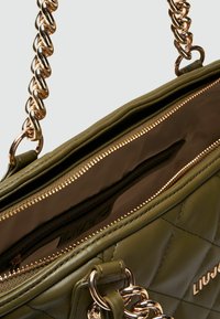 Borsa a tracolla trapuntata verde oliva con catena dorata. Presenta una tasca interna con cerniera e una superficie in pelle liscia. Etichettata all'interno.
