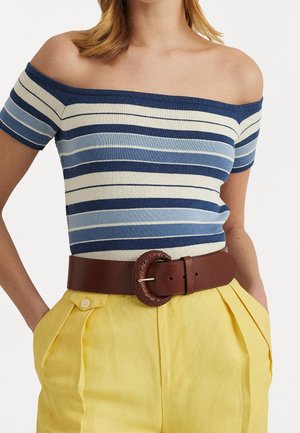 Top sin mangas a rayas en azul y crema, combinado con pantalones amarillos de pliegues y un cinturón marrón con una hebilla redonda trenzada.