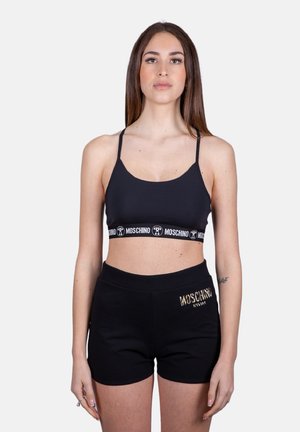 Top corto nero con spalline sottili e fascia con logo; abbinato a pantaloni corti neri con logo ricamato in oro sul lato. Tessuto misto cotone.