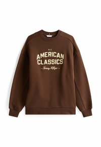 Bruine sweatshirt met ribbels bij de manchetten en onderrand. Heeft de tekst "ALL AMERICAN CLASSICS" in crèmekleur. Gemaakt van een gestructureerde, middelzware stof.