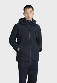 Námořnická modrá bunda s kapucí na zip, dvěma náprsními kapsami, nastavitelnými šňůrkami a rovný střih. Hladký, voděodolný materiál.