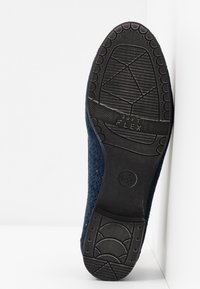 Semelle en caoutchouc noir d'une chaussure bleu marine avec motifs de grip texturés et texte « Soft Flex » au niveau de l'avant-pied, taille indiquée 37.